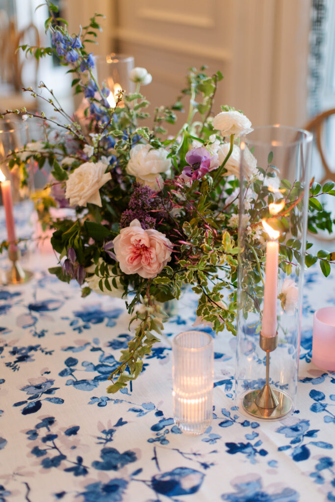 Garden-inspired centerpieces for spring wedding reception. Whimsical floral design with petal heavy florals in low compotes and bud vases. Pastel color palette for spring wedding which shades of pink, purple, lavender, and cream. Tasteful candlelight with mixed metals and pastel taper candles. Design by Rosemary & Finch Floral Design in Nashville, TN. 