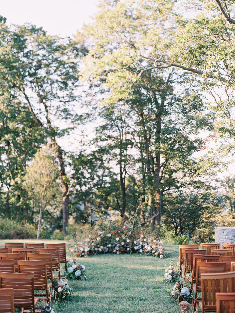 Lush garden floral meadow for fall wedding ceremony. Floral ground arch and organic aisle meadows with grassy textures and muted floral tones. Soft whimsical floral design for unique fall wedding design. Fall wedding color palette in brown, soft blue, dusty rose, and muted greens. Whimsical florals featuring dried hydrangeas, tulips, delphinium, and grasses. Design by Rosemary & Finch Floral Design in Nashville, TN. 