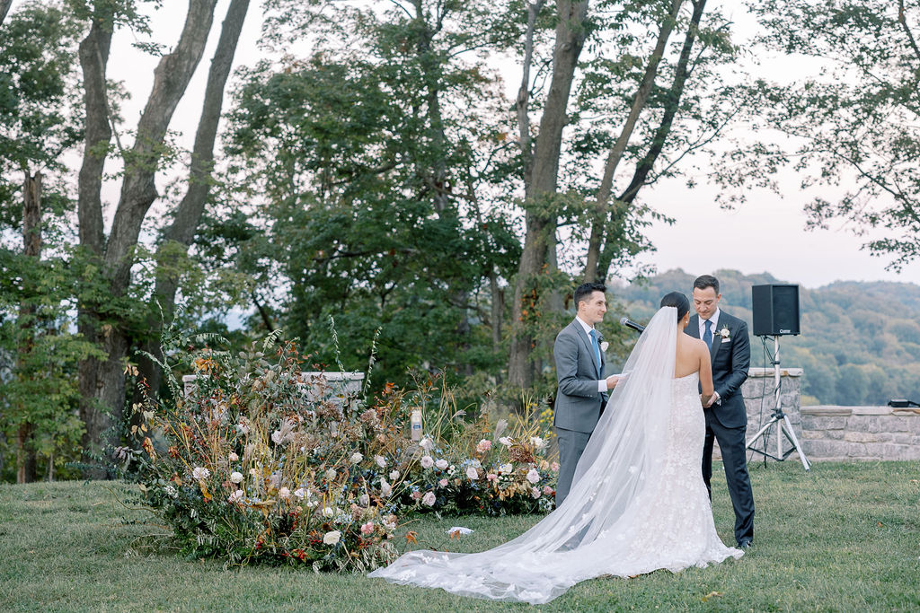 Lush garden floral meadow for fall wedding ceremony. Floral ground arch and organic aisle meadows with grassy textures and muted floral tones. Soft whimsical floral design for unique fall wedding design. Fall wedding color palette in brown, soft blue, dusty rose, and muted greens. Whimsical florals featuring dried hydrangeas, tulips, delphinium, and grasses. Design by Rosemary & Finch Floral Design in Nashville, TN. 