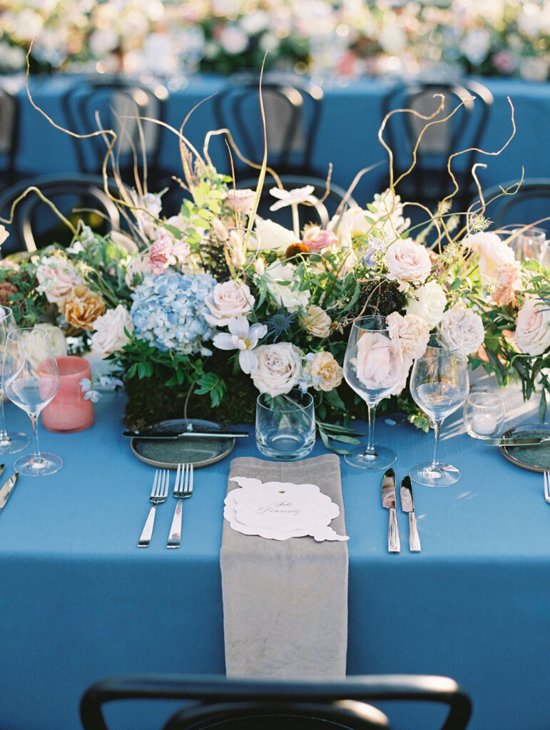 Lush floral table runner for fall wedding reception. Outdoor wedding reception at Southall Farm & Inn in Tennessee. Soft whimsical floral design for unique fall wedding design. Fall wedding color palette in brown, soft blue, dusty rose, and muted greens. Whimsical florals featuring dried hydrangeas, tulips, delphinium, and grasses. Design by Rosemary & Finch Floral Design in Nashville, TN. 