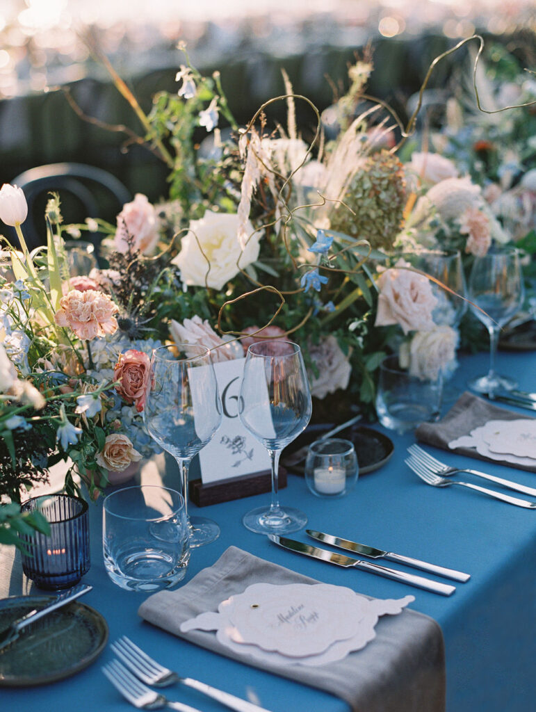 Lush floral table runner for fall wedding reception. Outdoor wedding reception at Southall Farm & Inn in Tennessee. Soft whimsical floral design for unique fall wedding design. Fall wedding color palette in brown, soft blue, dusty rose, and muted greens. Whimsical florals featuring dried hydrangeas, tulips, delphinium, and grasses. Design by Rosemary & Finch Floral Design in Nashville, TN. 