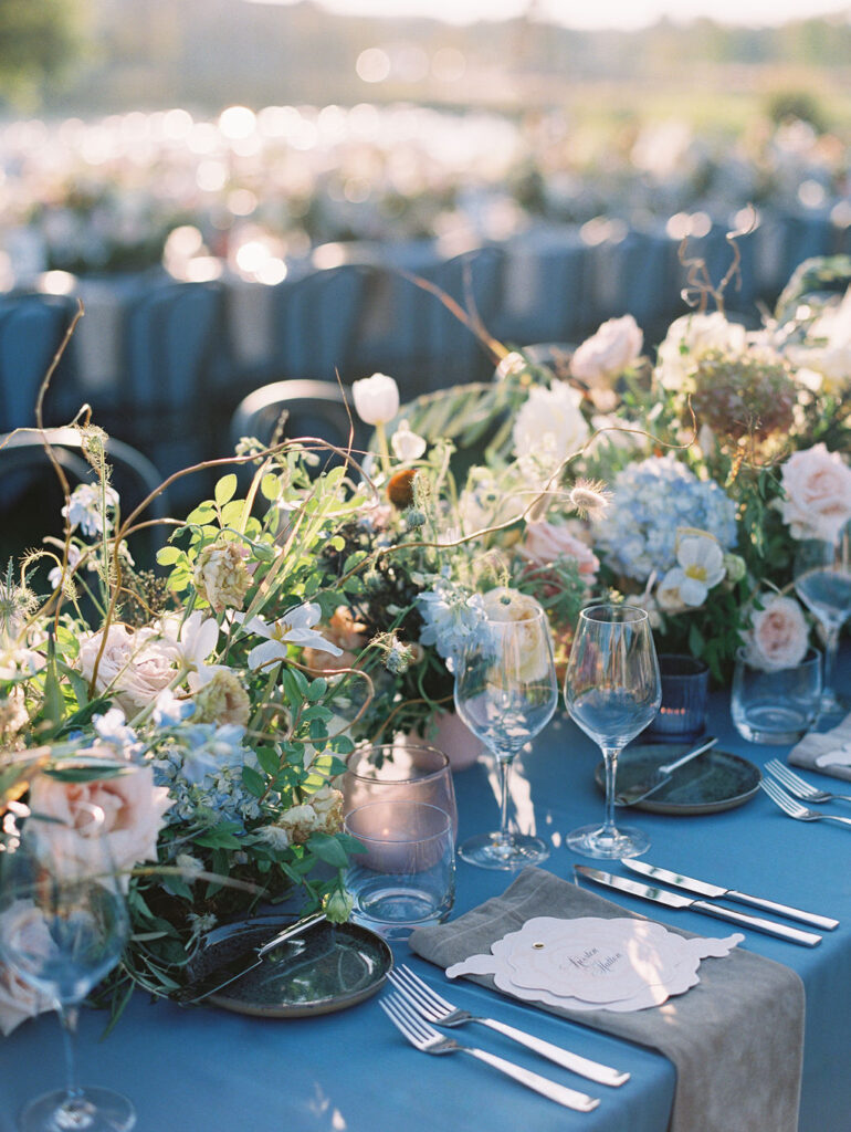 Lush floral table runner for fall wedding reception. Outdoor wedding reception at Southall Farm & Inn in Tennessee. Soft whimsical floral design for unique fall wedding design. Fall wedding color palette in brown, soft blue, dusty rose, and muted greens. Whimsical florals featuring dried hydrangeas, tulips, delphinium, and grasses. Design by Rosemary & Finch Floral Design in Nashville, TN. 