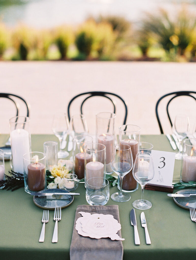 Candle heavy reception tables for outdoor wedding reception. Candlelight dinner for fall wedding with chocolate and taupe pillar candles. Curated candle design with blush and brown tone candles and votives. Soft whimsical floral design for unique fall wedding design. Fall wedding color palette in brown, soft blue, dusty rose, and muted greens. Design by Rosemary & Finch Floral Design in Nashville, TN. 