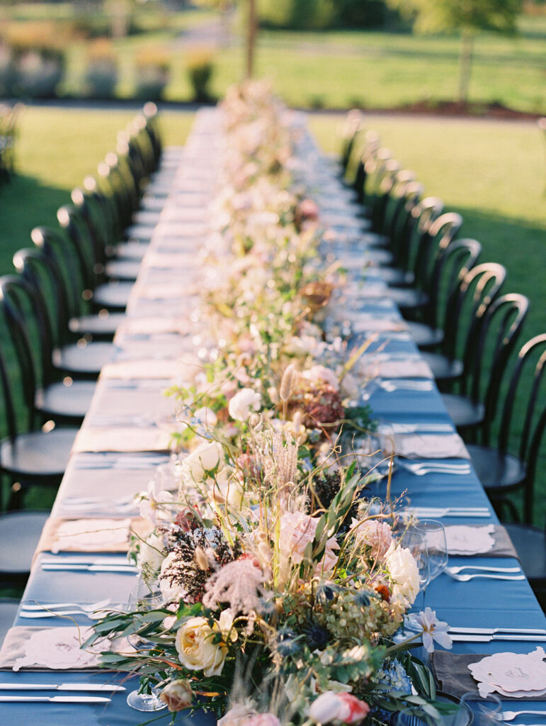 Lush floral table runner for fall wedding reception. Outdoor wedding reception at Southall Farm & Inn in Tennessee. Soft whimsical floral design for unique fall wedding design. Fall wedding color palette in brown, soft blue, dusty rose, and muted greens. Whimsical florals featuring dried hydrangeas, tulips, delphinium, and grasses. Design by Rosemary & Finch Floral Design in Nashville, TN. 