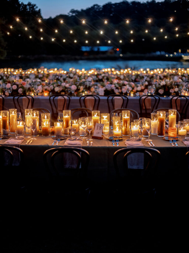 Candle heavy reception tables for outdoor wedding reception. Candlelight dinner for fall wedding with chocolate and taupe pillar candles. Curated candle design with blush and brown tone candles and votives. Soft whimsical floral design for unique fall wedding design. Fall wedding color palette in brown, soft blue, dusty rose, and muted greens. Design by Rosemary & Finch Floral Design in Nashville, TN. 