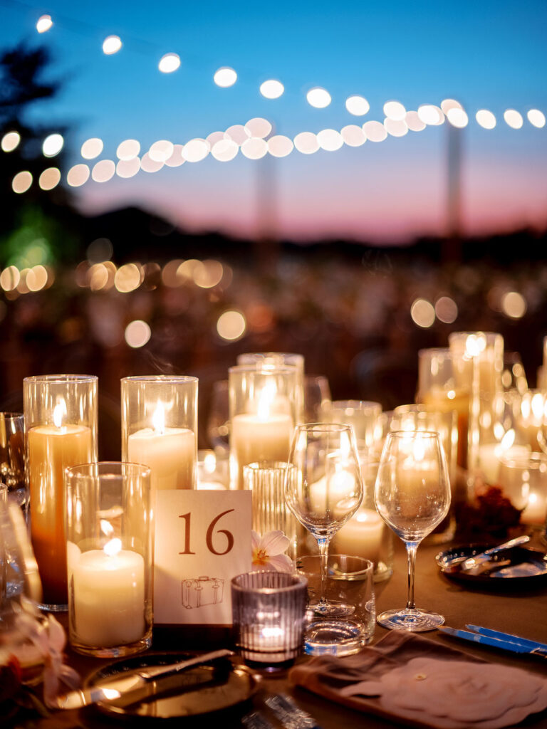 Candle heavy reception tables for outdoor wedding reception. Candlelight dinner for fall wedding with chocolate and taupe pillar candles. Curated candle design with blush and brown tone candles and votives. Soft whimsical floral design for unique fall wedding design. Fall wedding color palette in brown, soft blue, dusty rose, and muted greens. Design by Rosemary & Finch Floral Design in Nashville, TN. 