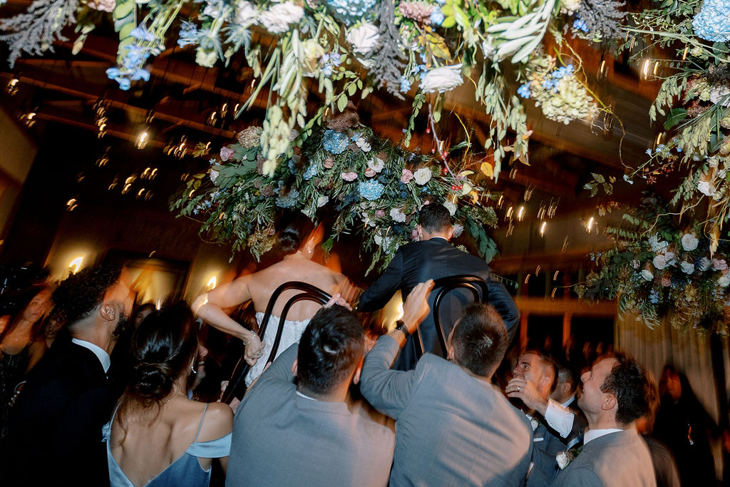 Epic floral clouds for reception dance floor. Floral clouds perfectly frame the stage for this fall wedding reception. Soft whimsical floral design for unique fall wedding design. Fall wedding color palette in brown, soft blue, dusty rose, and muted greens. Whimsical florals featuring dried hydrangeas, tulips, delphinium, and grasses. Design by Rosemary & Finch Floral Design in Nashville, TN.