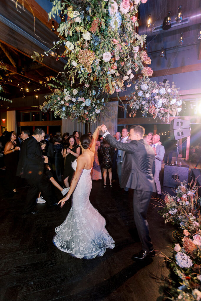 Epic floral clouds for reception dance floor. Floral clouds perfectly frame the stage for this fall wedding reception. Soft whimsical floral design for unique fall wedding design. Fall wedding color palette in brown, soft blue, dusty rose, and muted greens. Whimsical florals featuring dried hydrangeas, tulips, delphinium, and grasses. Design by Rosemary & Finch Floral Design in Nashville, TN.