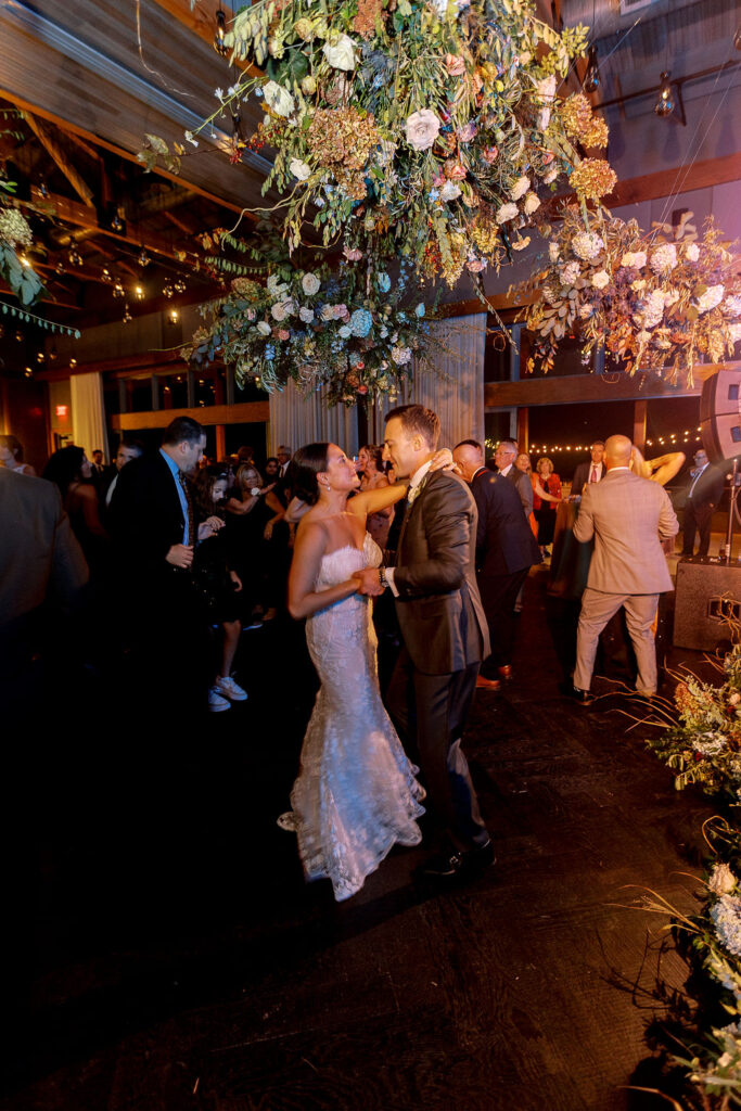 Epic floral clouds for reception dance floor. Floral clouds perfectly frame the stage for this fall wedding reception. Soft whimsical floral design for unique fall wedding design. Fall wedding color palette in brown, soft blue, dusty rose, and muted greens. Whimsical florals featuring dried hydrangeas, tulips, delphinium, and grasses. Design by Rosemary & Finch Floral Design in Nashville, TN.