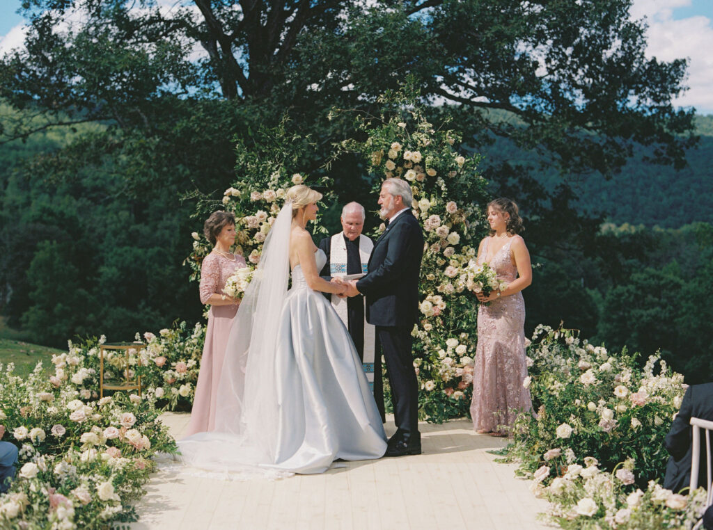 Epic ceremony backdrop for fall wedding at Blackberry Farms. Lush broken arch floral design for wedding ceremony backdrop. Garden inspired growing floral in colors of cream, white, blush, and green. Full coverage floral aisle for wedding ceremony. Floral meadows with petal heavy roses. Floral heavy flora design with elegant and whimsical design. Destination wedding at Blackberry Farm. Design by Rosemary & Finch Floral Design in Nashville, TN. 