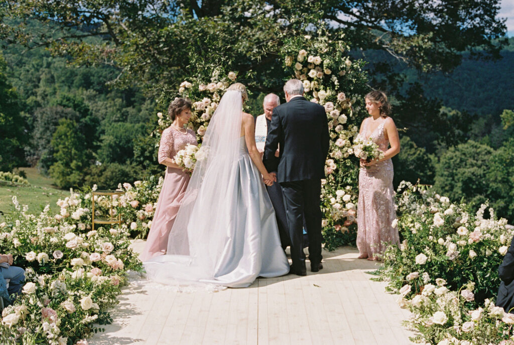 Epic ceremony backdrop for fall wedding at Blackberry Farms. Lush broken arch floral design for wedding ceremony backdrop. Garden inspired growing floral in colors of cream, white, blush, and green. Full coverage floral aisle for wedding ceremony. Floral meadows with petal heavy roses. Floral heavy flora design with elegant and whimsical design. Destination wedding at Blackberry Farm. Design by Rosemary & Finch Floral Design in Nashville, TN. 