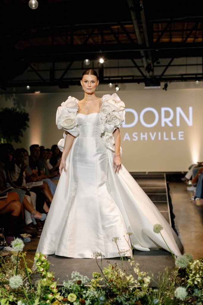 Garden-inspired, whimsical arrangements for bridal fashion show in Nashville, TN. Floral arrangements feature texture and movement, with Queen Anne’s lace, oncidium orchids, blue nigella, lisianthus, zinnias, amaranthus, allium, coneflower, smokebush, forget me nots and airy grasses. With earthy greens, soft whites, golden yellow, mauve and burgundy, the flowers spill out and showcase a meadow-like focal point for a fashion runway. Design by Rosemary & Finch Floral Design in Nashville, TN.