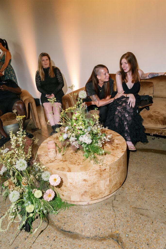 Lush, garden-inspired cocktail hour floral arrangement for bridal fashion show in Nashville, TN. The flowers overflow with texture and movement, featuring Queen Anne’s lace, oncidium orchids, lisianthus, amaranthus, and airy grasses. With earthy greens, soft whites, golden yellow, and touches of mauve and burgundy, the flowers spill naturally, creating a whimsical, meadow-like focal point for a modern lounge setting. Design by Rosemary & Finch Floral Design in Nashville, TN.