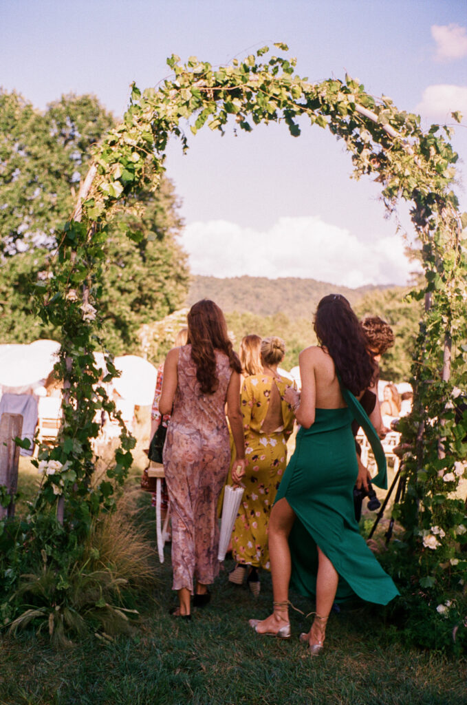 Elegant, organic and untamed outdoor wedding ceremony at Blackberry Farms featured in Vogue. Whimsical, grassy meadows line the aisle and floral accents are highlighted with white cosmos, green mist, solidago, yarrow, scabiosa and grasses. Pergola is covered in lush greenery with soft touches of cream roses and wispy meadows at the base. Design by Rosemary & Finch Floral Design in Nashville, TN. 
