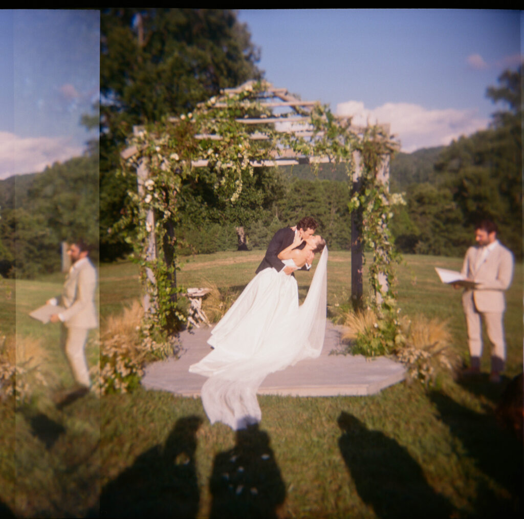 Elegant, organic and untamed outdoor wedding ceremony at Blackberry Farms featured in Vogue. Whimsical, grassy meadows line the aisle and floral accents are highlighted with white cosmos, green mist, solidago, yarrow, scabiosa and grasses. Pergola is covered in lush greenery with soft touches of cream roses and wispy meadows at the base. Design by Rosemary & Finch Floral Design in Nashville, TN. 