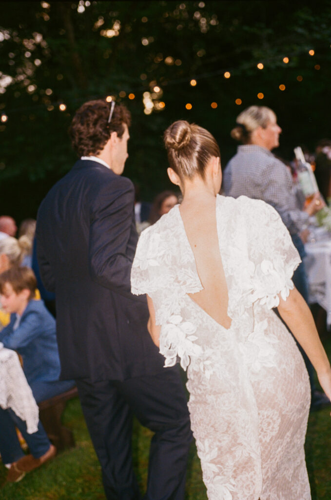Romantic and timeless outdoor garden wedding reception featured in Vogue at Blackberry Farms. The floral design highlights white seasonal wildflowers such as cosmos, Queen Anne’s lace, sweet peas, clematis, and saponaria, with touches of texture including flowering smokebush, maidenhair fern, and herbs for a garden-inspired style atop lace table linens. Warm candlelight and soft tones create a sophisticated and intimate atmosphere. Design by Rosemary & Finch Floral Design in Nashville, TN.