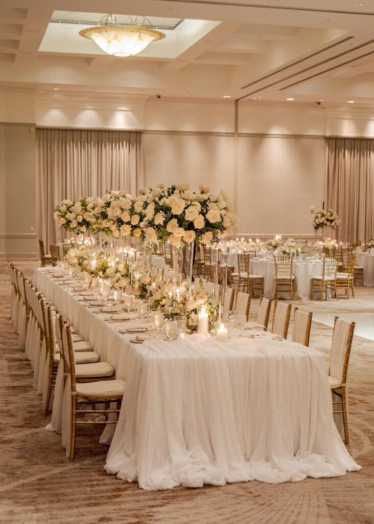 Stunning reception florals for summer wedding reception in Buckhead, Atlanta. All-white floral centerpieces featuring cloud roses, playa blanca roses, peonies, ranunculus, double tulips and lisianthus. Minimal greenery complements beautiful floral table arrangements and bud vases. Elevated all-white rose centerpieces scattered throughout reception. Design by Rosemary & Finch Floral Design in Nashville, TN.