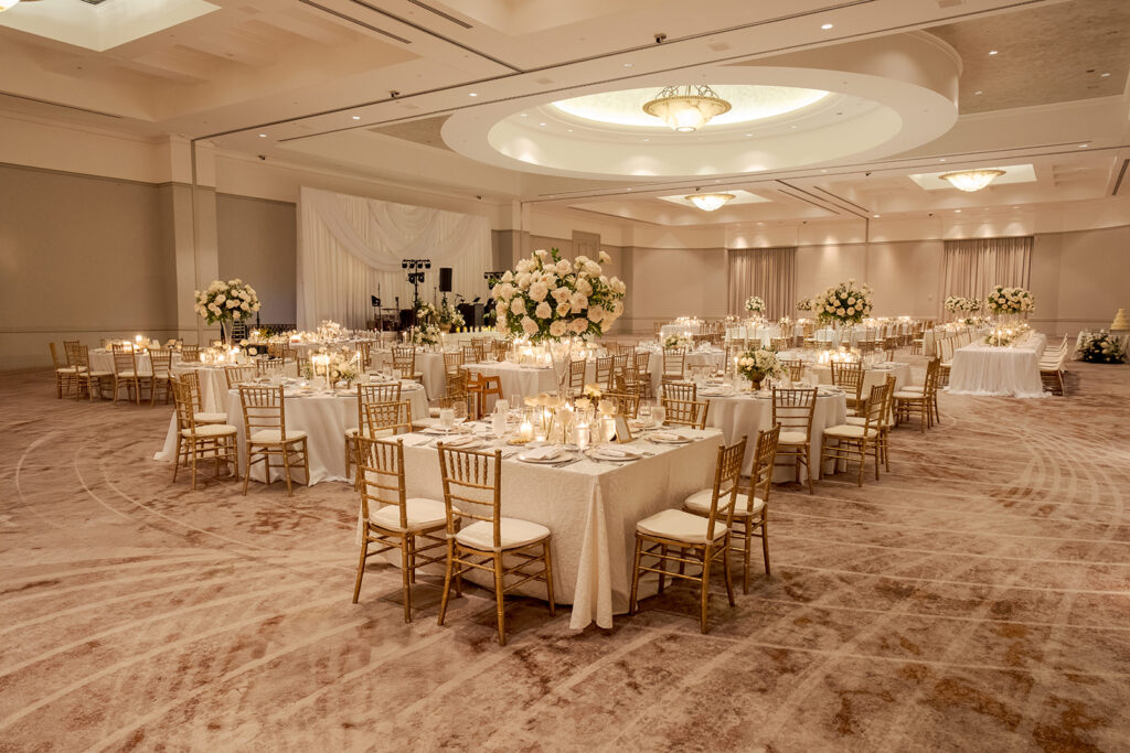 Stunning reception florals for summer wedding reception in Buckhead, Atlanta. All-white floral centerpieces featuring cloud roses, playa blanca roses, peonies, ranunculus, double tulips and lisianthus. Minimal greenery complements beautiful floral table arrangements and bud vases. Elevated all-white rose centerpieces scattered throughout reception. Design by Rosemary & Finch Floral Design in Nashville, TN.