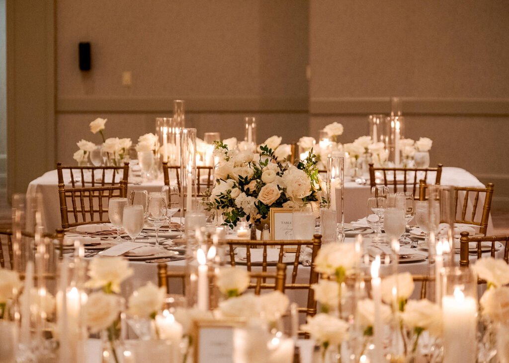 Stunning reception florals for summer wedding reception in Buckhead, Atlanta. All-white floral centerpieces featuring cloud roses, playa blanca roses, peonies, ranunculus, double tulips and lisianthus. Minimal greenery complements beautiful floral table arrangements and bud vases. Elevated all-white rose centerpieces scattered throughout reception. Design by Rosemary & Finch Floral Design in Nashville, TN.