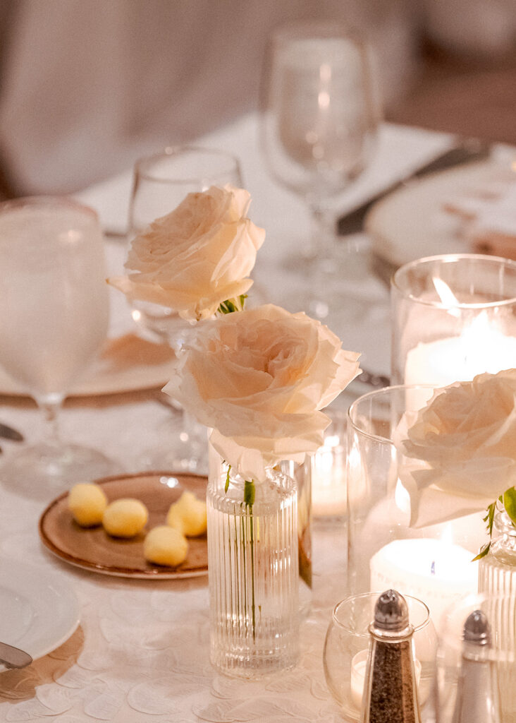 Stunning reception florals for summer wedding reception in Buckhead, Atlanta. All-white floral centerpieces featuring cloud roses, playa blanca roses, peonies, ranunculus, double tulips and lisianthus. Minimal greenery complements beautiful floral table arrangements and bud vases. Elevated all-white rose centerpieces scattered throughout reception. Design by Rosemary & Finch Floral Design in Nashville, TN.