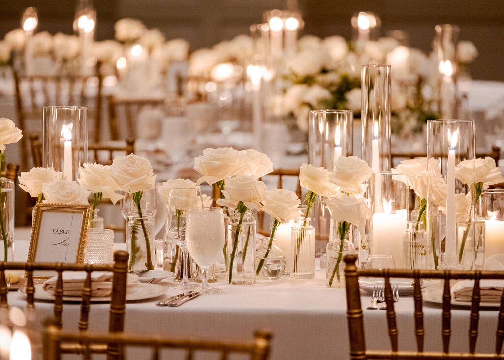 Stunning reception florals for summer wedding reception in Buckhead, Atlanta. All-white floral centerpieces featuring cloud roses, playa blanca roses, peonies, ranunculus, double tulips and lisianthus. Minimal greenery complements beautiful floral table arrangements and bud vases. Elevated all-white rose centerpieces scattered throughout reception. Design by Rosemary & Finch Floral Design in Nashville, TN.