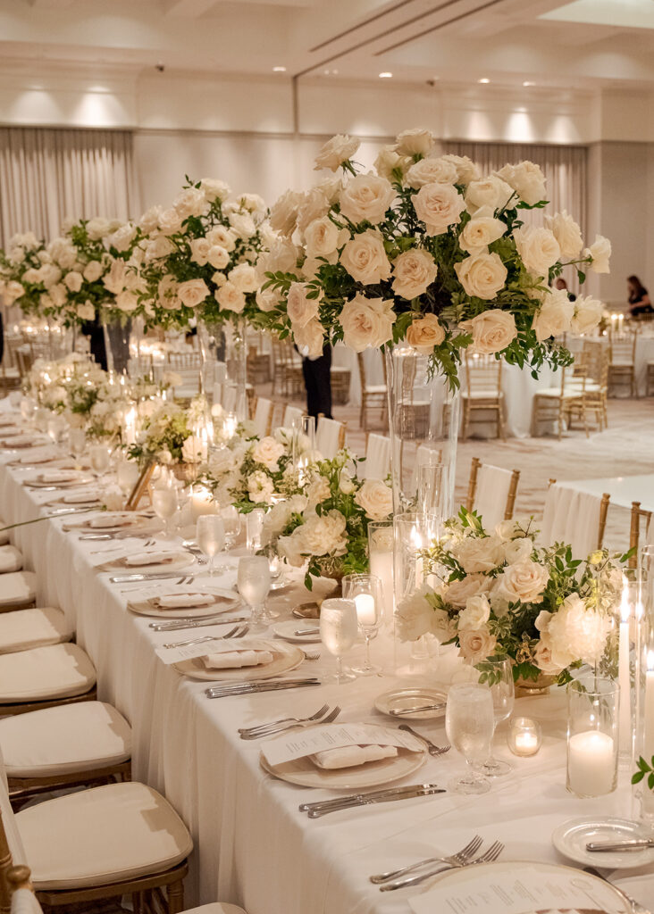 Stunning reception florals for summer wedding reception in Buckhead, Atlanta. All-white floral centerpieces featuring cloud roses, playa blanca roses, peonies, ranunculus, double tulips and lisianthus. Minimal greenery complements beautiful floral table arrangements and bud vases. Elevated all-white rose centerpieces scattered throughout reception. Design by Rosemary & Finch Floral Design in Nashville, TN.