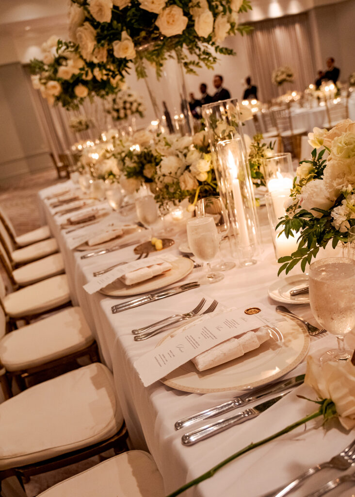 Stunning reception florals for summer wedding reception in Buckhead, Atlanta. All-white floral centerpieces featuring cloud roses, playa blanca roses, peonies, ranunculus, double tulips and lisianthus. Minimal greenery complements beautiful floral table arrangements and bud vases. Elevated all-white rose centerpieces scattered throughout reception. Design by Rosemary & Finch Floral Design in Nashville, TN.