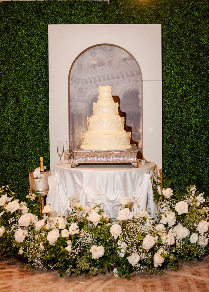 Stunning cocktail hour florals for wedding reception in Buckhead, Atlanta. All-white florals featuring cloud roses, playa blanca roses, peonies, ranunculus, delphinium, baby’s breath, double tulips and lisianthus. Soft and romantic floral cake arrangement for summer wedding. Design by Rosemary & Finch Floral Design in Nashville, TN.