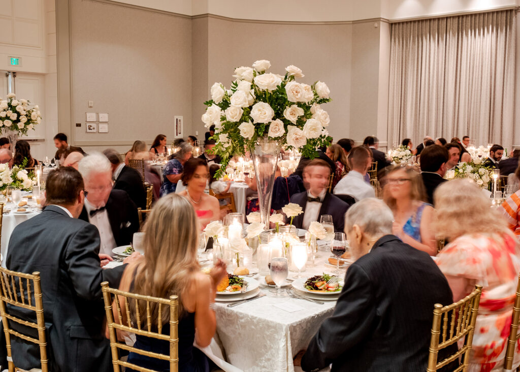 Stunning reception florals for summer wedding reception in Buckhead, Atlanta. All-white floral centerpieces featuring cloud roses, playa blanca roses, peonies, ranunculus, double tulips and lisianthus. Minimal greenery complements beautiful floral table arrangements and bud vases. Elevated all-white rose centerpieces scattered throughout reception. Design by Rosemary & Finch Floral Design in Nashville, TN.