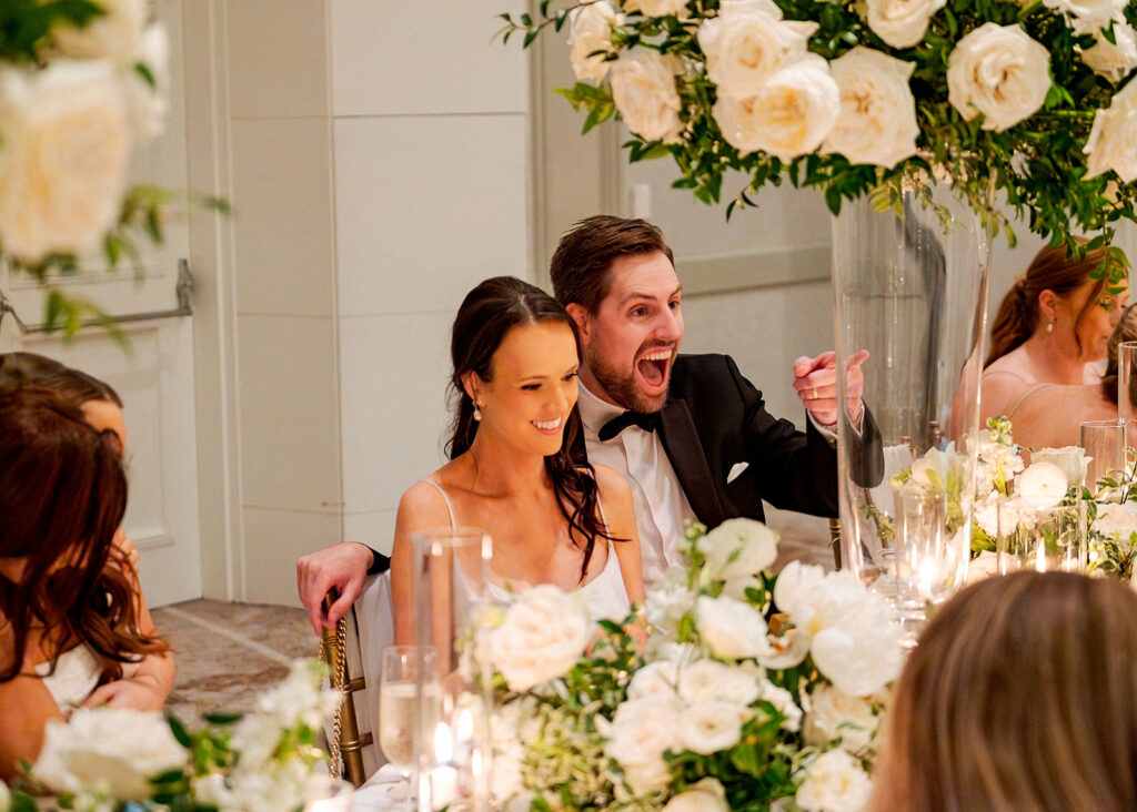 Stunning reception florals for summer wedding reception in Buckhead, Atlanta. All-white floral centerpieces featuring cloud roses, playa blanca roses, peonies, ranunculus, double tulips and lisianthus. Minimal greenery complements beautiful floral table arrangements and bud vases. Elevated all-white rose centerpieces scattered throughout reception. Design by Rosemary & Finch Floral Design in Nashville, TN.