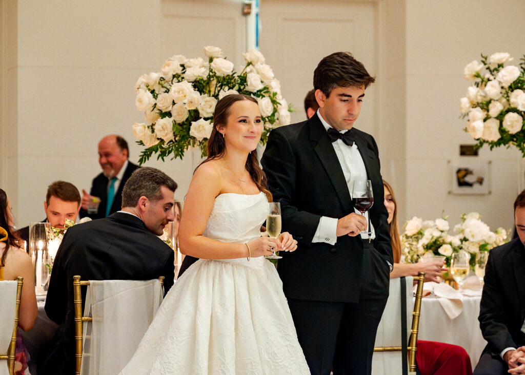 Stunning reception florals for summer wedding reception in Buckhead, Atlanta. All-white floral centerpieces featuring cloud roses, playa blanca roses, peonies, ranunculus, double tulips and lisianthus. Minimal greenery complements beautiful floral table arrangements and bud vases. Elevated all-white rose centerpieces scattered throughout reception. Design by Rosemary & Finch Floral Design in Nashville, TN.