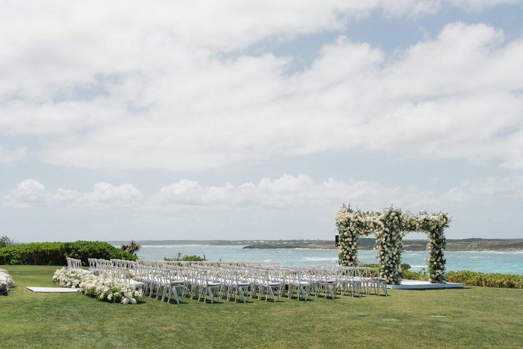 Lush and romantic ceremony chuppah florals for beachfront wedding in the Bahamas. The chuppah highlights garden roses, hydrangeas, delphinium, spray roses, baby’s breath, chrysanthemums, oncidium, wisteria, tulips and a mixture of airy greens to create an elegant and dramatic focal point. Layered textures and soft movement blend seamlessly with lush aisle meadows featuring the same flowers as the chuppah. Design by Rosemary & Finch Floral Design in Nashville, TN.