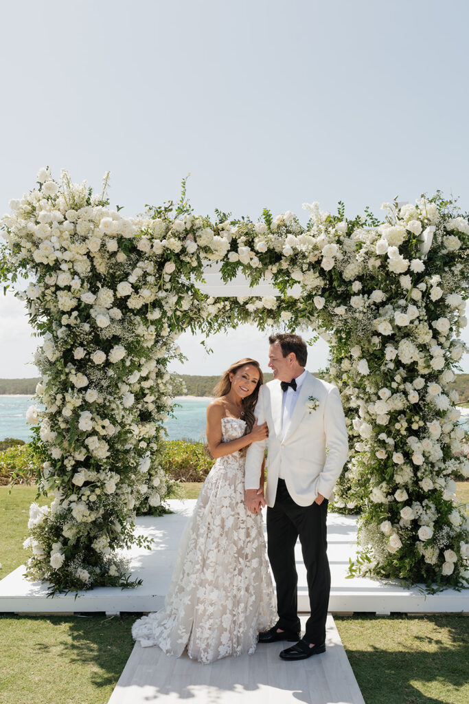 Lush and romantic ceremony chuppah florals for beachfront wedding in the Bahamas. The chuppah highlights garden roses, hydrangeas, delphinium, spray roses, baby’s breath, chrysanthemums, oncidium, wisteria, tulips and a mixture of airy greens to create an elegant and dramatic focal point. Layered textures and soft movement blend seamlessly with lush aisle meadows featuring the same flowers as the chuppah. Design by Rosemary & Finch Floral Design in Nashville, TN.