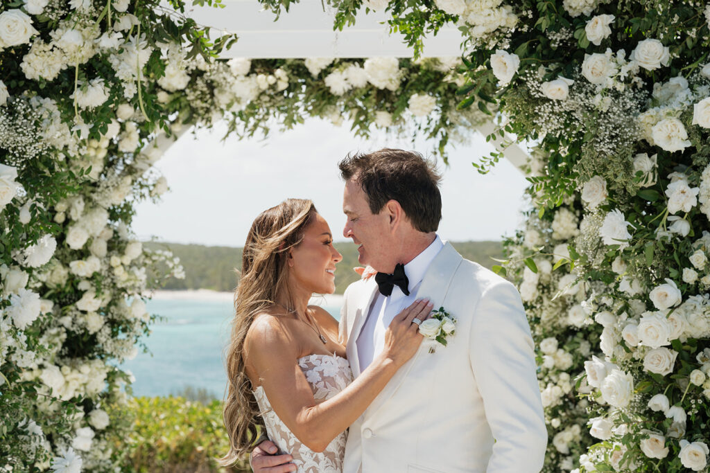 Lush and romantic ceremony chuppah florals for beachfront wedding in the Bahamas. The chuppah highlights garden roses, hydrangeas, delphinium, spray roses, baby’s breath, chrysanthemums, oncidium, wisteria, tulips and a mixture of airy greens to create an elegant and dramatic focal point. Layered textures and soft movement blend seamlessly with lush aisle meadows featuring the same flowers as the chuppah. Design by Rosemary & Finch Floral Design in Nashville, TN.