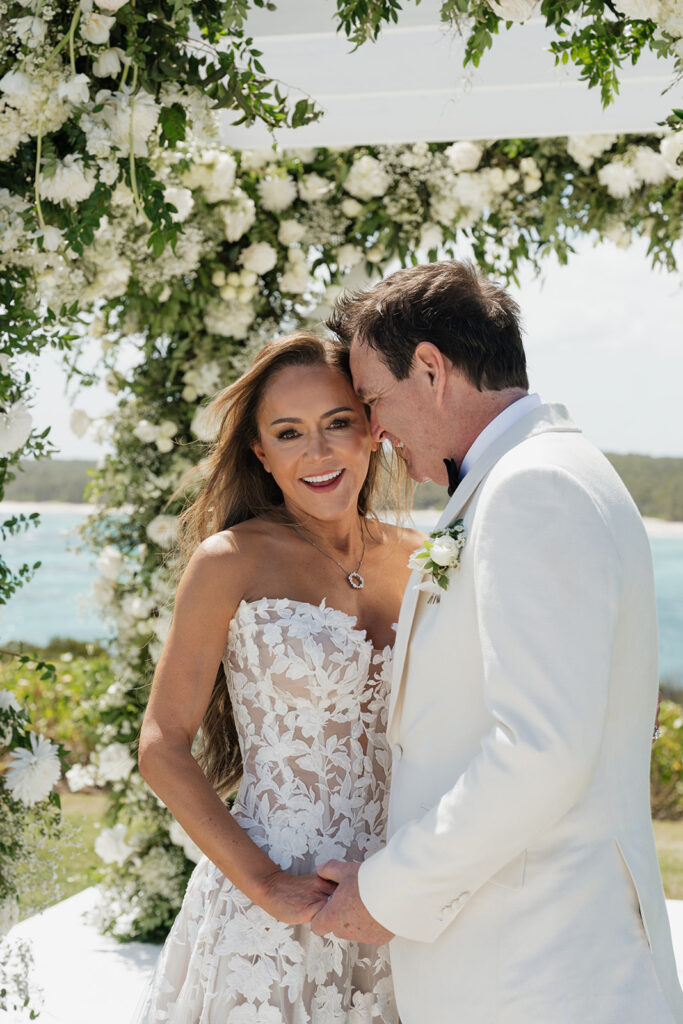 Lush, editorial bridal bouquet featuring all-white garden roses, ranunculus, delphinium, waxflower, oncidium, lisianthus, jasmine, sweet peas, tulips, clematis and a small mix of greenery. A slight hue of butter yellow is featured as well. Soft and romantic bouquet to highlight the airiness of a beachfront wedding in the Bahamas. Design by Rosemary & Finch Floral Design in Nashville, TN. 