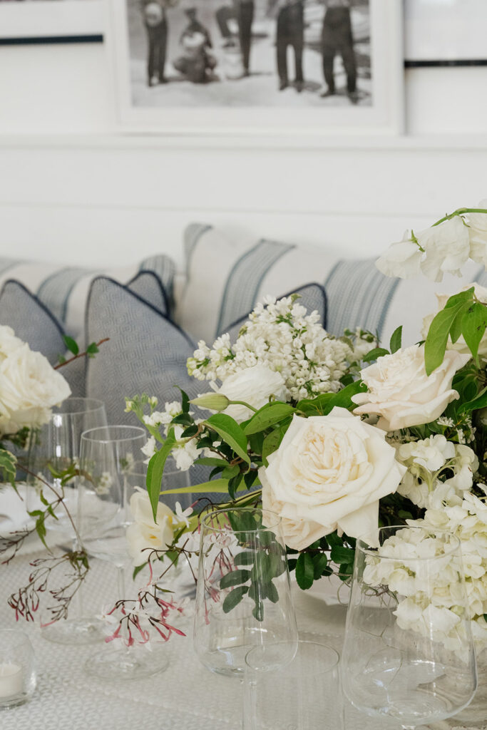 Ethereal white wedding reception with a breathtaking canopy of cascading white wisteria & green vines. Tables feature low, lush centerpieces combining garden roses, hydrangeas, spray roses, waxflower, delphinium, ranunculus, tulips, oncidium orchids, lisianthus, tweedia, lilac, sweet peas and are accented by deep-green foliage. This stunning floral design creates a luxurious, romantic, all-white atmosphere. Design by Rosemary & Finch Floral Design in Nashville, TN. 