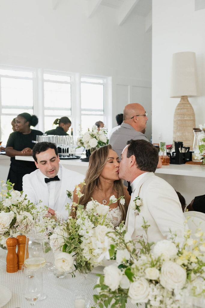 Ethereal white wedding reception with a breathtaking canopy of cascading white wisteria & green vines. Tables feature low, lush centerpieces combining garden roses, hydrangeas, spray roses, waxflower, delphinium, ranunculus, tulips, oncidium orchids, lisianthus, tweedia, lilac, sweet peas and are accented by deep-green foliage. This stunning floral design creates a luxurious, romantic, all-white atmosphere. Design by Rosemary & Finch Floral Design in Nashville, TN. 