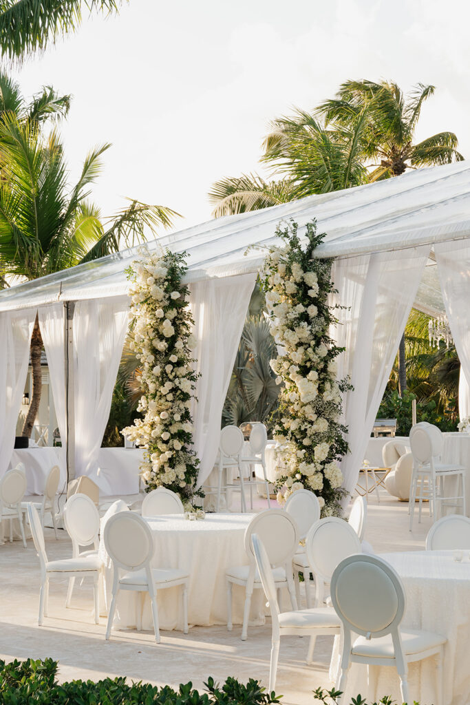 Simple, romantic all white floral bud vase arrangements for stunning bahamas cocktail hour. Bud vases are accompanied by all-white statement piece arrangements featuring garden roses, hydrangeas, spray roses, waxflower, delphinium, ranunculus, tulips, oncidium orchids, lisianthus, tweedia, lilac, sweet peas and are accented by a mix of greenery. Design by Rosemary & Finch Floral Design in Nashville, TN. 
