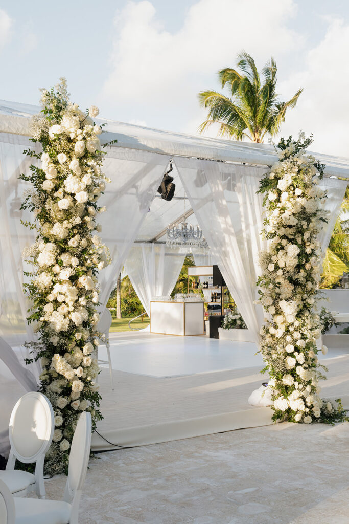 Simple, romantic all white floral bud vase arrangements for stunning bahamas cocktail hour. Bud vases are accompanied by all-white statement piece arrangements featuring garden roses, hydrangeas, spray roses, waxflower, delphinium, ranunculus, tulips, oncidium orchids, lisianthus, tweedia, lilac, sweet peas and are accented by a mix of greenery. Design by Rosemary & Finch Floral Design in Nashville, TN. 
