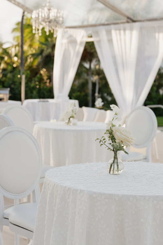Simple, romantic all white floral bud vase arrangements for stunning bahamas cocktail hour. Bud vases are accompanied by all-white statement piece arrangements featuring garden roses, hydrangeas, spray roses, waxflower, delphinium, ranunculus, tulips, oncidium orchids, lisianthus, tweedia, lilac, sweet peas and are accented by a mix of greenery. Design by Rosemary & Finch Floral Design in Nashville, TN. 
