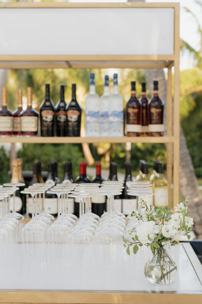Simple, romantic all white floral bud vase arrangements for stunning bahamas cocktail hour. Bud vases are accompanied by all-white statement piece arrangements featuring garden roses, hydrangeas, spray roses, waxflower, delphinium, ranunculus, tulips, oncidium orchids, lisianthus, tweedia, lilac, sweet peas and are accented by a mix of greenery. Design by Rosemary & Finch Floral Design in Nashville, TN. 
