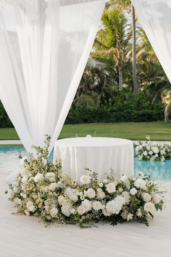 Simple, romantic all white floral bud vase arrangements for stunning bahamas cocktail hour. Bud vases are accompanied by all-white statement piece arrangements featuring garden roses, hydrangeas, spray roses, waxflower, delphinium, ranunculus, tulips, oncidium orchids, lisianthus, tweedia, lilac, sweet peas and are accented by a mix of greenery. Design by Rosemary & Finch Floral Design in Nashville, TN. 
