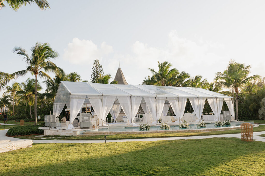 Simple, romantic all white floral bud vase arrangements for stunning bahamas cocktail hour. Bud vases are accompanied by all-white statement piece arrangements featuring garden roses, hydrangeas, spray roses, waxflower, delphinium, ranunculus, tulips, oncidium orchids, lisianthus, tweedia, lilac, sweet peas and are accented by a mix of greenery. Design by Rosemary & Finch Floral Design in Nashville, TN. 
