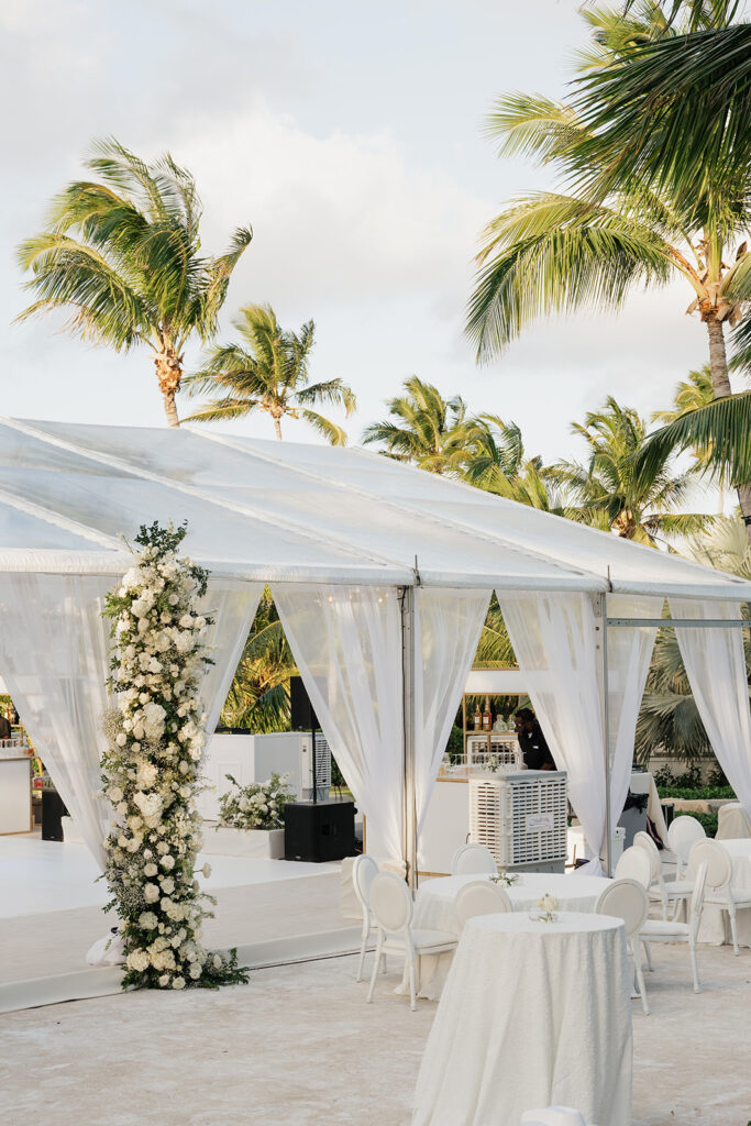 Simple, romantic all white floral bud vase arrangements for stunning bahamas cocktail hour. Bud vases are accompanied by all-white statement piece arrangements featuring garden roses, hydrangeas, spray roses, waxflower, delphinium, ranunculus, tulips, oncidium orchids, lisianthus, tweedia, lilac, sweet peas and are accented by a mix of greenery. Design by Rosemary & Finch Floral Design in Nashville, TN. 

