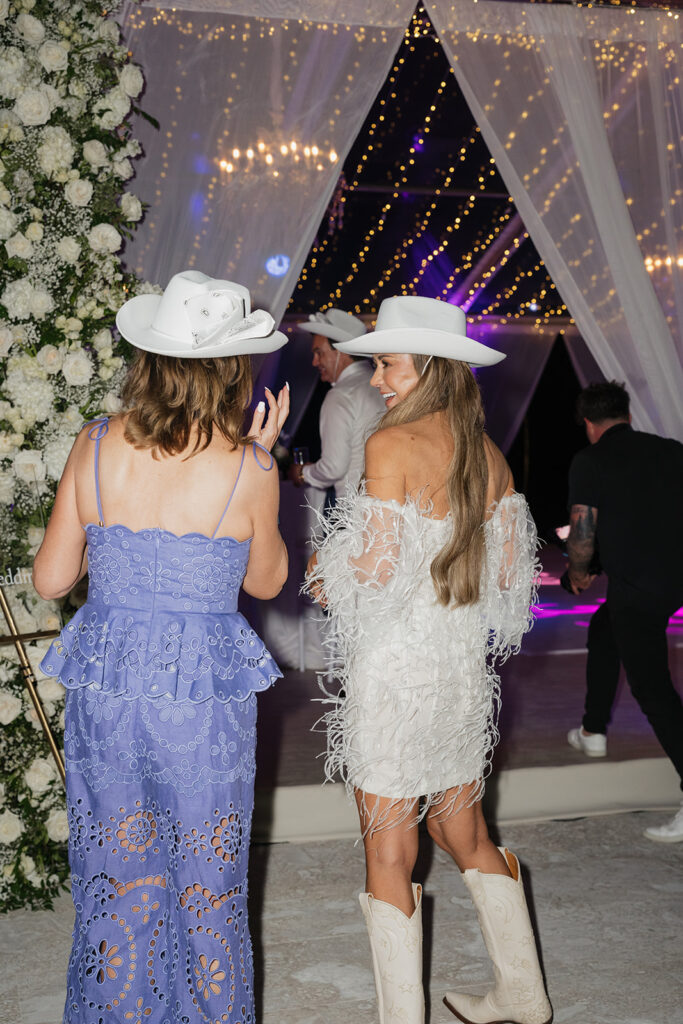 Ethereal white wedding reception with a breathtaking low, lush centerpieces combining garden roses, hydrangeas, spray roses, waxflower, delphinium, ranunculus, tulips, oncidium orchids, lisianthus, tweedia, lilac, sweet peas and are accented by deep-green foliage. This stunning floral design creates a luxurious, romantic, all-white atmosphere. Design by Rosemary & Finch Floral Design in Nashville, TN. 