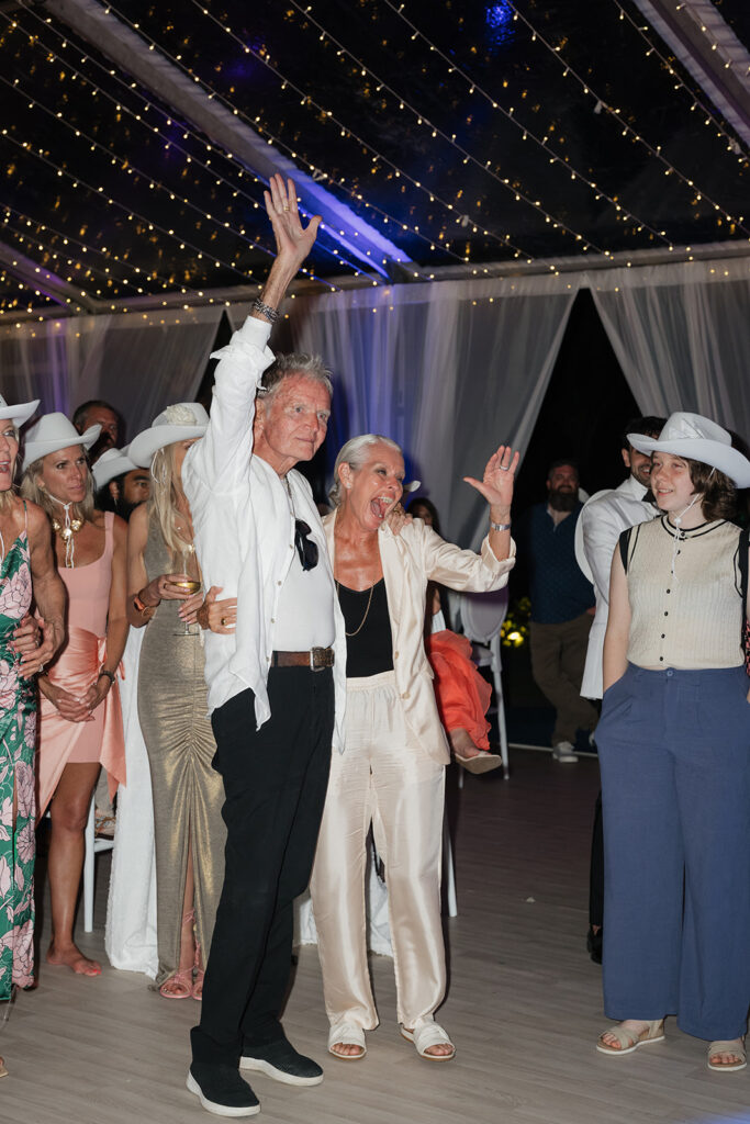 Ethereal white wedding reception with a breathtaking low, lush centerpieces combining garden roses, hydrangeas, spray roses, waxflower, delphinium, ranunculus, tulips, oncidium orchids, lisianthus, tweedia, lilac, sweet peas and are accented by deep-green foliage. This stunning floral design creates a luxurious, romantic, all-white atmosphere. Design by Rosemary & Finch Floral Design in Nashville, TN. 