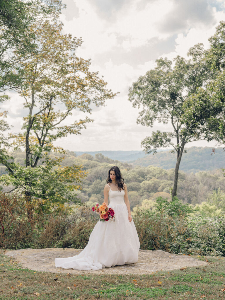 An autumnal, simple bridal bouquet displaying colors of burgundy, blush, rusty orange, and peach. Stunning florals include dahlias, garden roses, moab roses, cappuccino roses, brown ranunculus, zinnias, chocolate cosmos, brown sweet peas, toffee lisianthus, yarrow, marigolds and amaranthus. Beautiful fall florals for a wedding at Southall, TN. Design by Rosemary and Finch Floral Design in Nashville, TN.