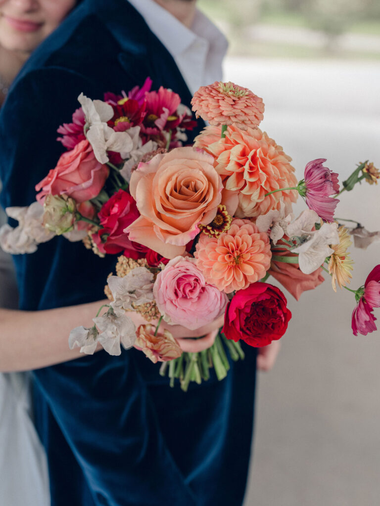 An autumnal, simple bridal bouquet displaying colors of burgundy, blush, rusty orange, and peach. Stunning florals include dahlias, garden roses, moab roses, cappuccino roses, brown ranunculus, zinnias, chocolate cosmos, brown sweet peas, toffee lisianthus, yarrow, marigolds and amaranthus. Beautiful fall florals for a wedding at Southall, TN. Design by Rosemary and Finch Floral Design in Nashville, TN.