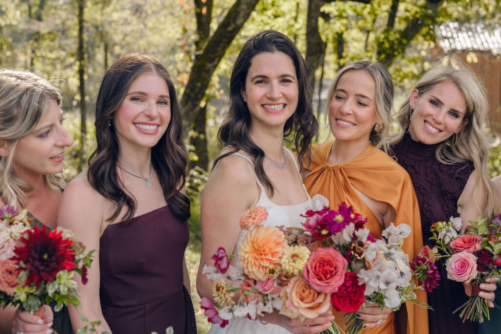 An autumnal, simple bridal bouquet displaying colors of burgundy, blush, rusty orange, and peach. Stunning florals include dahlias, garden roses, moab roses, cappuccino roses, brown ranunculus, zinnias, chocolate cosmos, brown sweet peas, toffee lisianthus, yarrow, marigolds and amaranthus. Beautiful fall florals for a wedding at Southall, TN. Design by Rosemary and Finch Floral Design in Nashville, TN.
