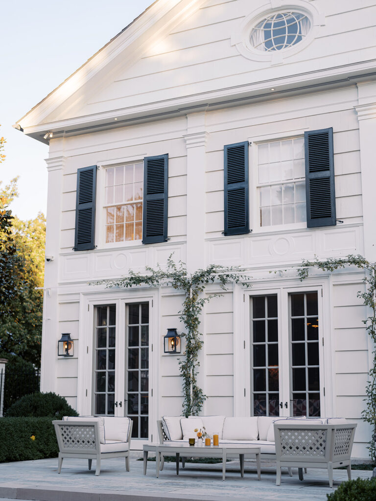 White ceramic bud vases with light florals scattered throughout cocktail hour for a private birthday party event in Nashville, TN. Bud vases consist of light greenery, peach dahlias, explosion grass, amber ranunculus, toffee lisianthus, copper zinnias, red marigolds, clematis pods, and nigella. Design by Rosemary and Finch Floral Design in Nashville, TN. 